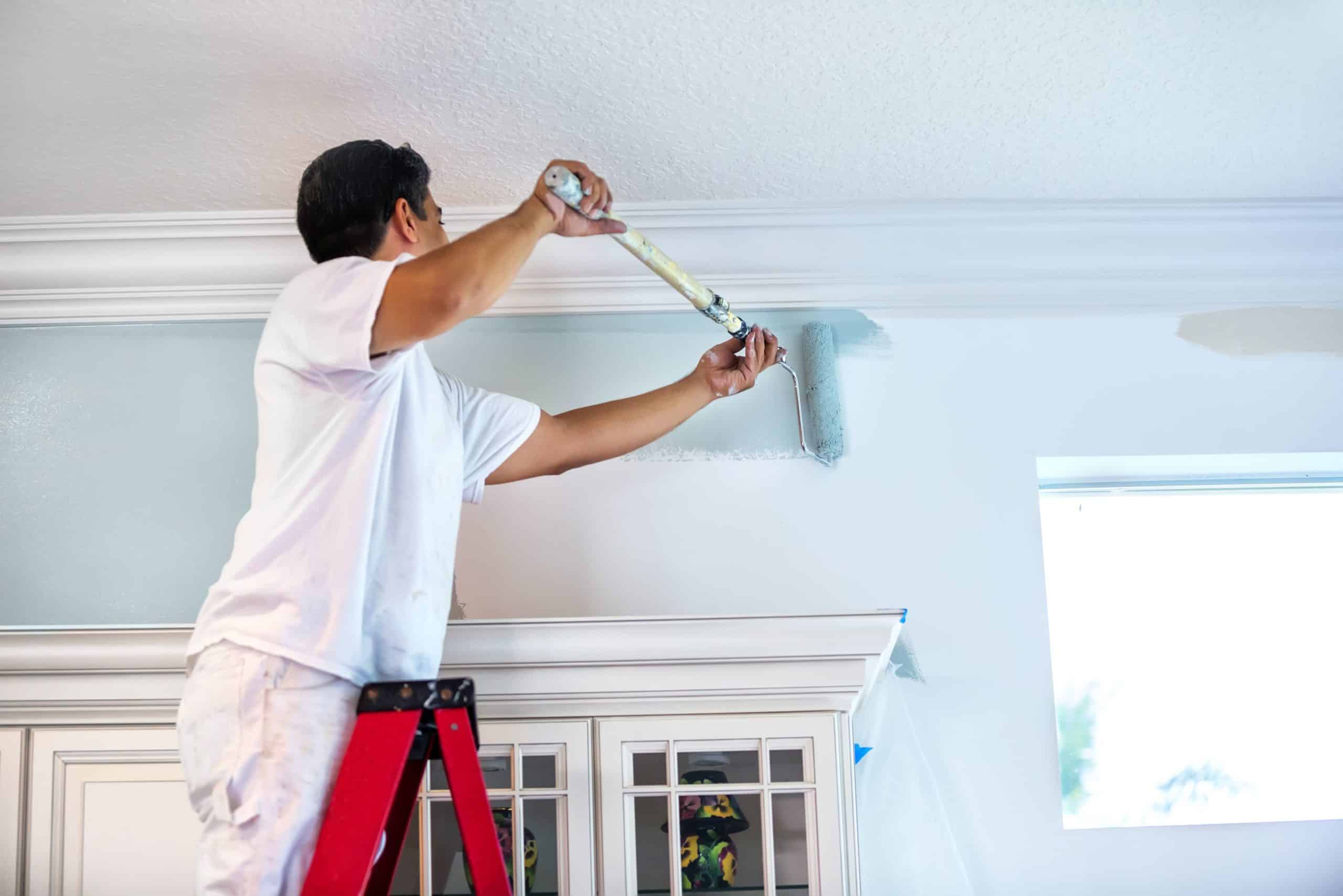 a man painting the ceiling of a kitchen in a gallery